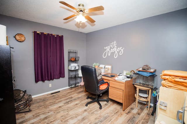 home office featuring ceiling fan, light wood-type flooring, and a textured ceiling