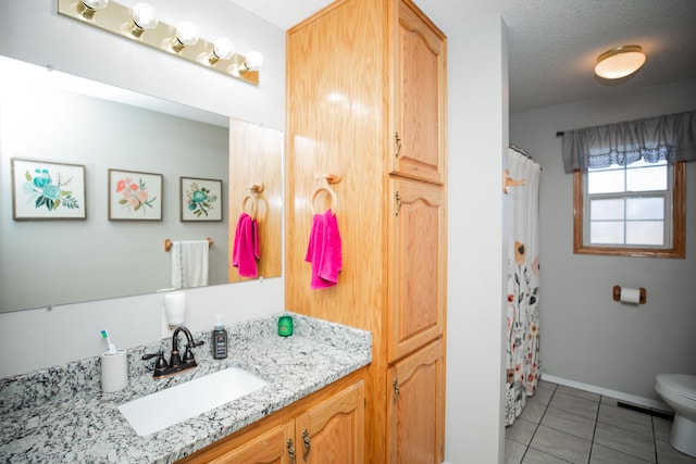 bathroom featuring tile patterned floors, vanity, toilet, and a textured ceiling