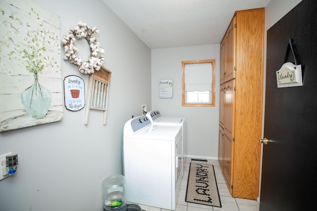 laundry room with washer and dryer, light tile patterned floors, a textured ceiling, and cabinets