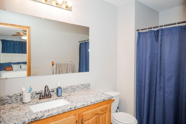 bathroom with ceiling fan, toilet, a textured ceiling, and vanity