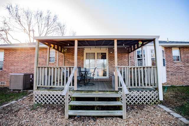 rear view of property featuring a wooden deck and central AC