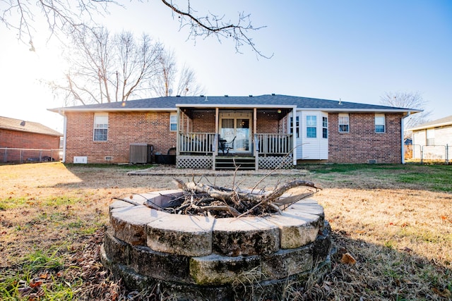 rear view of house with a lawn, central air condition unit, an outdoor fire pit, and a wooden deck