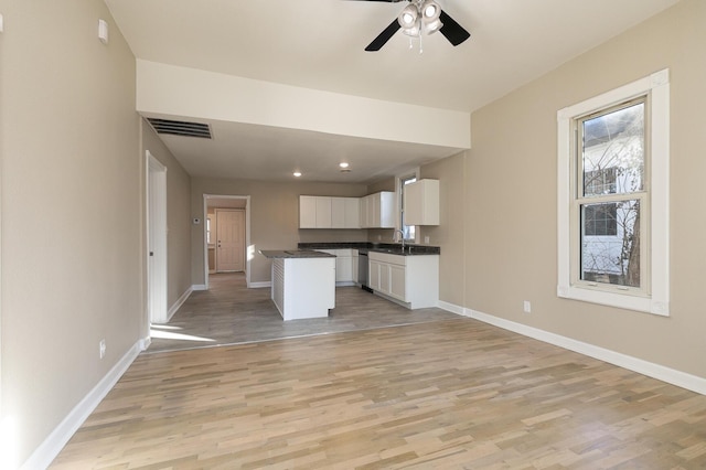 kitchen with white cabinets, a center island, light wood-type flooring, and sink