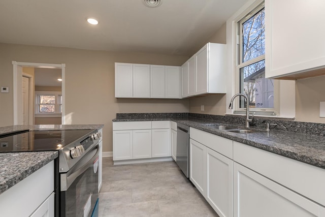 kitchen with dark stone countertops, white cabinetry, sink, and appliances with stainless steel finishes