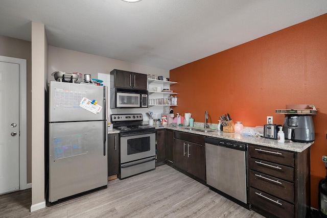 kitchen featuring sink, stainless steel appliances, light stone counters, light hardwood / wood-style flooring, and dark brown cabinets