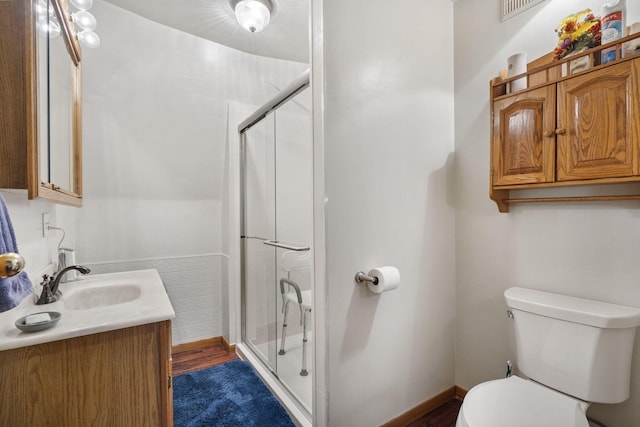 bathroom featuring walk in shower, hardwood / wood-style flooring, vanity, and toilet