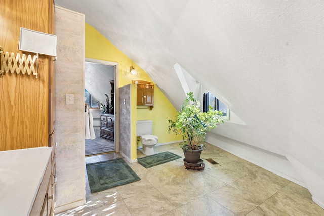 interior space featuring a textured ceiling, lofted ceiling, and light tile patterned flooring