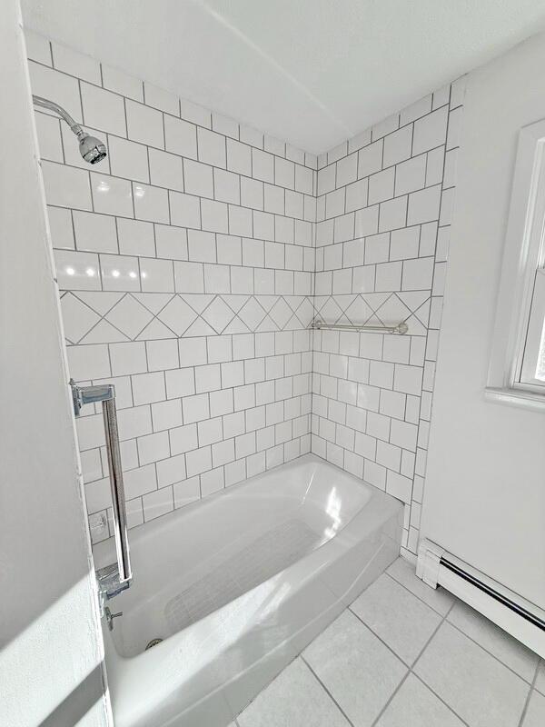 bathroom featuring baseboard heating, tile patterned floors, and tiled shower / bath combo