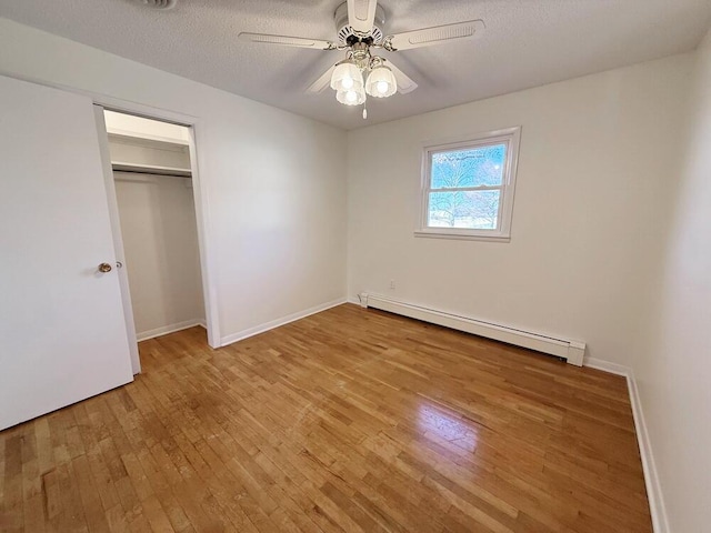 unfurnished bedroom featuring light wood-type flooring, a textured ceiling, ceiling fan, a baseboard radiator, and a closet