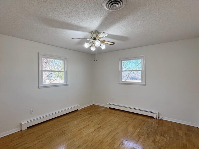 empty room with light hardwood / wood-style floors, a wealth of natural light, and a baseboard radiator