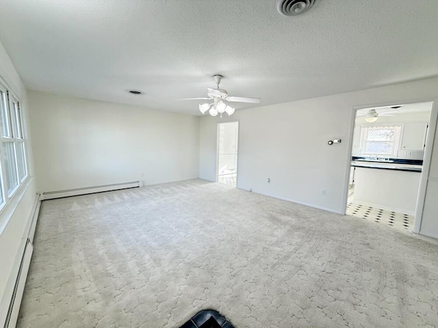 carpeted spare room with ceiling fan, a textured ceiling, and a baseboard heating unit