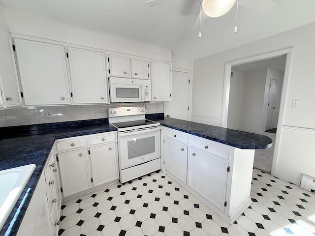 kitchen with kitchen peninsula, white appliances, and white cabinetry