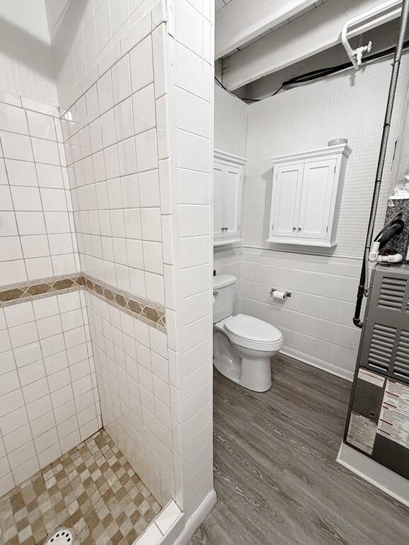 bathroom featuring a tile shower, hardwood / wood-style flooring, and toilet