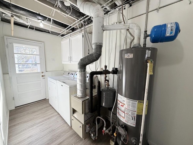 clothes washing area featuring cabinets, gas water heater, light hardwood / wood-style flooring, and washing machine and clothes dryer