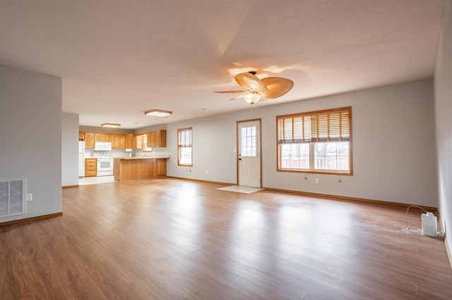 unfurnished living room featuring ceiling fan, light hardwood / wood-style floors, and a textured ceiling