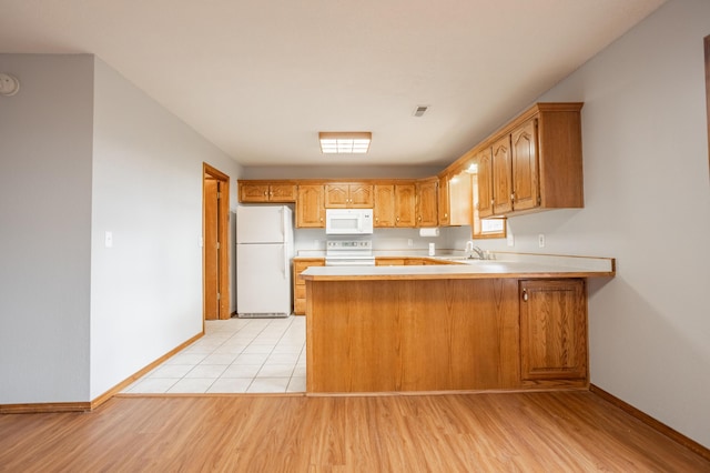 kitchen featuring kitchen peninsula, white appliances, light hardwood / wood-style flooring, and sink