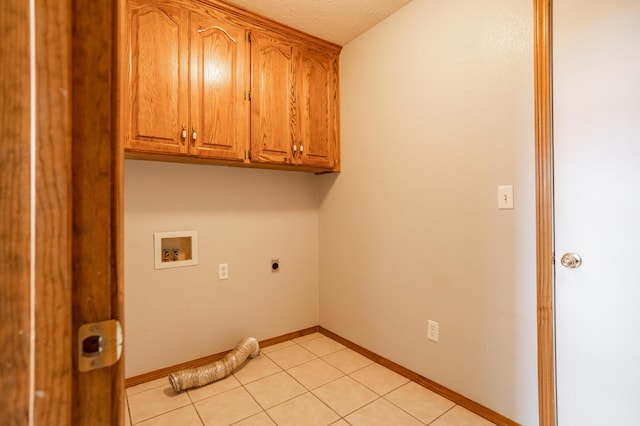 laundry room with electric dryer hookup, hookup for a washing machine, light tile patterned flooring, and cabinets