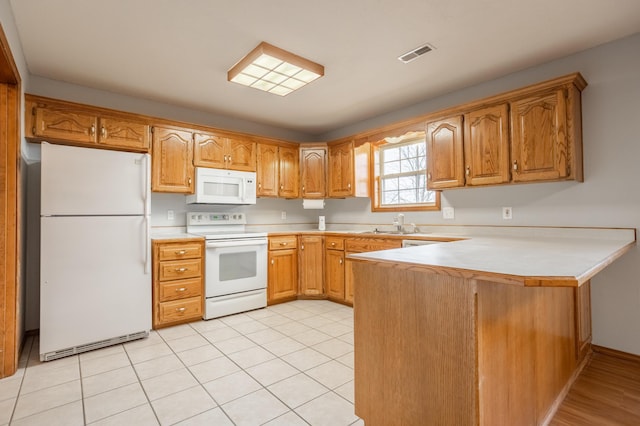 kitchen featuring kitchen peninsula, light tile patterned floors, white appliances, and sink