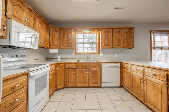 kitchen with kitchen peninsula, light tile patterned flooring, white appliances, and sink