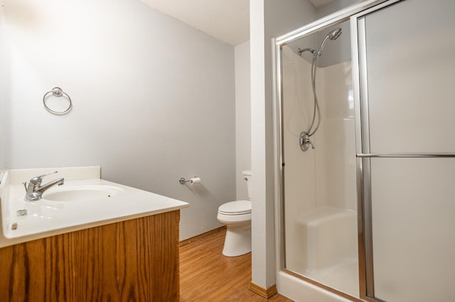 bathroom with wood-type flooring, vanity, toilet, and walk in shower