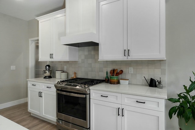 kitchen featuring backsplash, white cabinetry, gas range, light hardwood / wood-style floors, and custom range hood