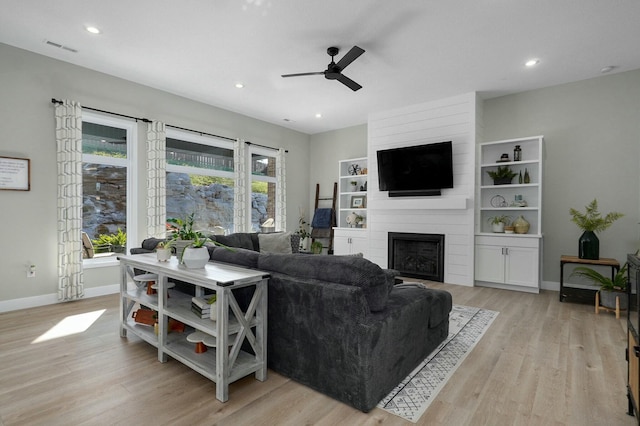 living room featuring ceiling fan, a healthy amount of sunlight, light wood-type flooring, and a fireplace