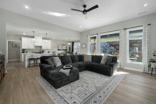 living room with a wealth of natural light, light hardwood / wood-style flooring, and ceiling fan