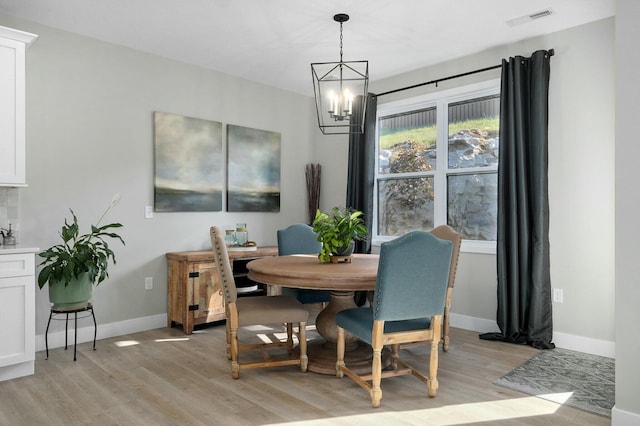 dining area with light hardwood / wood-style flooring and a notable chandelier