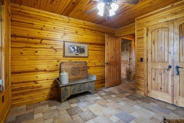 entryway featuring ceiling fan, wooden walls, and wood ceiling