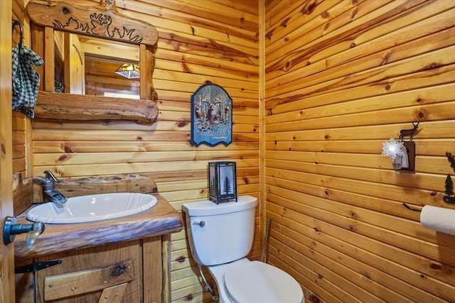 bathroom featuring vanity, wood walls, and toilet