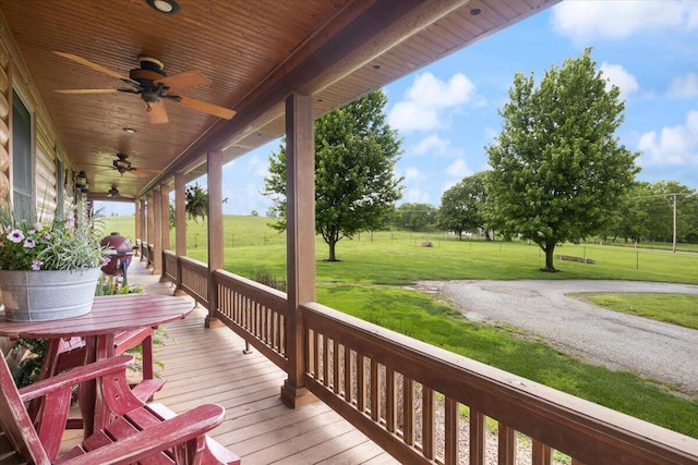 wooden deck featuring a lawn, ceiling fan, and a porch