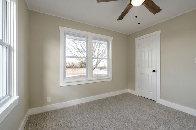 carpeted empty room featuring ceiling fan, plenty of natural light, and crown molding