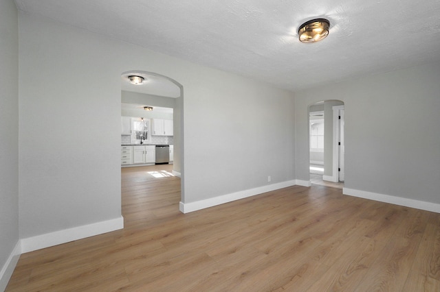 empty room with light hardwood / wood-style floors, sink, and a textured ceiling