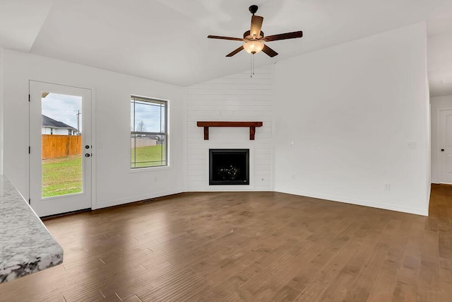 unfurnished living room featuring lofted ceiling, a ceiling fan, wood finished floors, and a fireplace