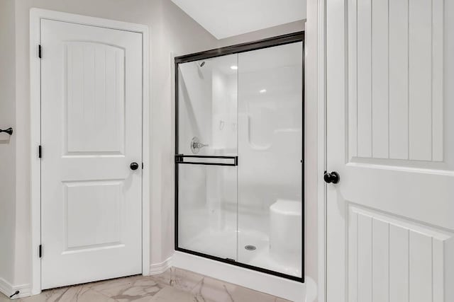 bathroom featuring a shower stall and marble finish floor