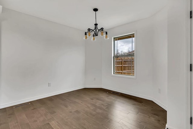 empty room with visible vents, baseboards, a notable chandelier, and dark wood-style flooring