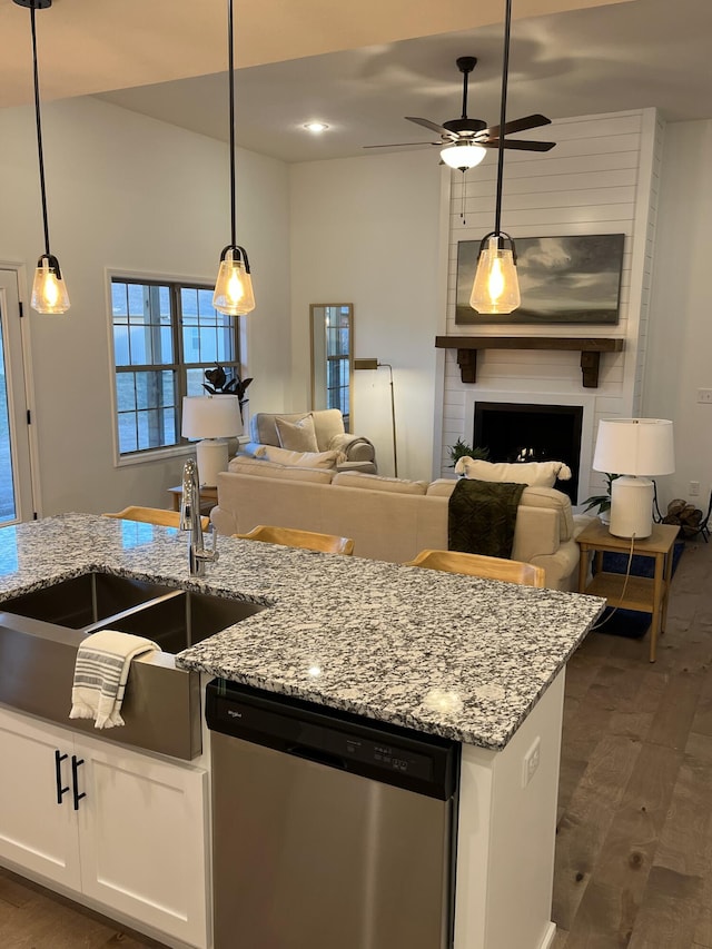 kitchen with a large fireplace, dark wood finished floors, open floor plan, stainless steel dishwasher, and a sink