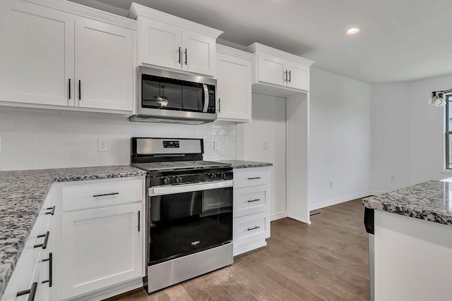 kitchen with stone counters, light wood-style floors, appliances with stainless steel finishes, and white cabinets