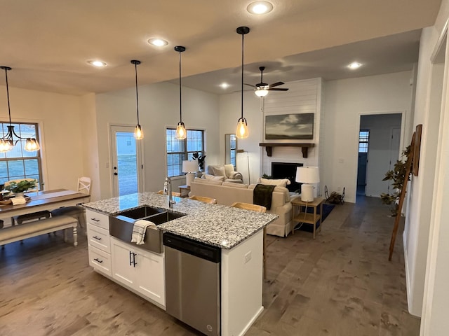 kitchen featuring a center island with sink, dishwasher, wood finished floors, white cabinets, and a sink