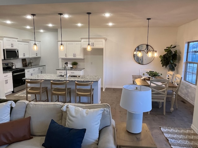 interior space with stainless steel microwave, open floor plan, gas range, white cabinetry, and a sink