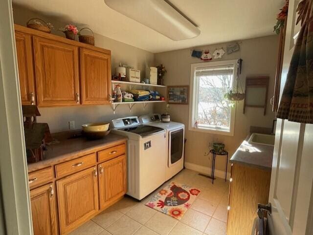 clothes washing area with cabinets, light tile patterned floors, and washer and clothes dryer