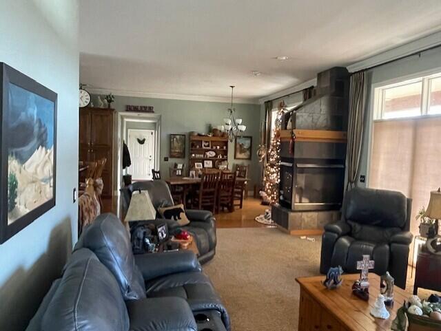 carpeted living room featuring ornamental molding, a fireplace, and a chandelier