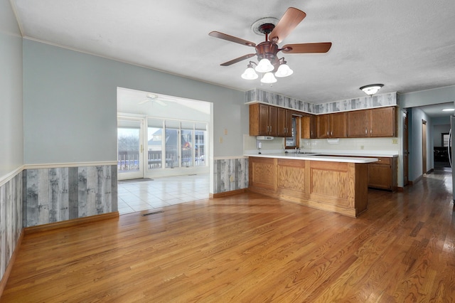 kitchen featuring kitchen peninsula, wooden walls, a textured ceiling, and light wood-type flooring