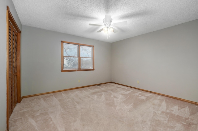 unfurnished bedroom with ceiling fan, a closet, light carpet, and a textured ceiling