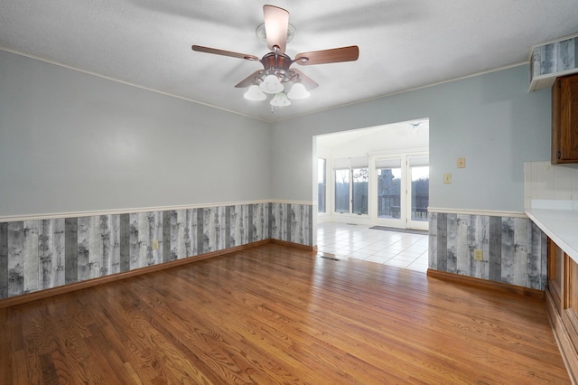 unfurnished living room with ceiling fan, crown molding, light hardwood / wood-style floors, and a textured ceiling