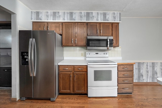 kitchen featuring a textured ceiling, wood-type flooring, and stainless steel appliances