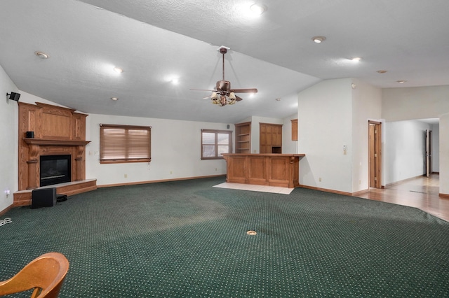 unfurnished living room with ceiling fan, a large fireplace, carpet floors, and vaulted ceiling