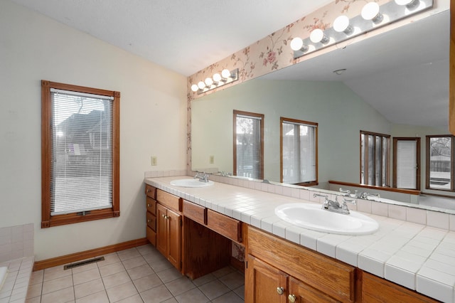 bathroom with tile patterned floors, a bathtub, vanity, and vaulted ceiling