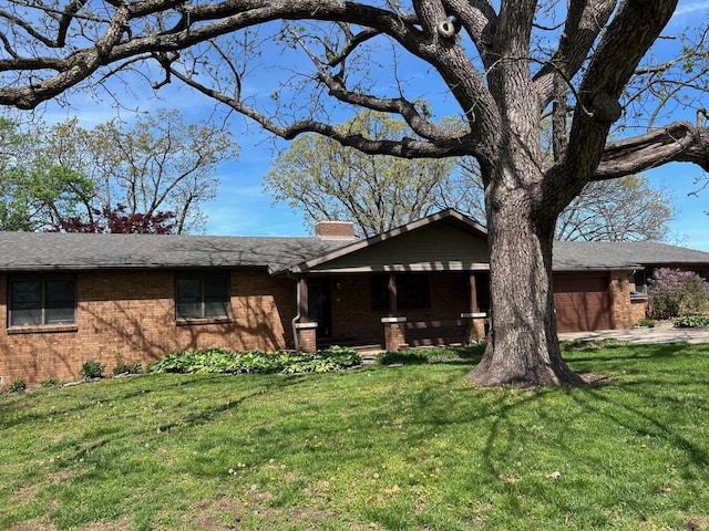 ranch-style house with an attached garage, a chimney, a front lawn, and brick siding