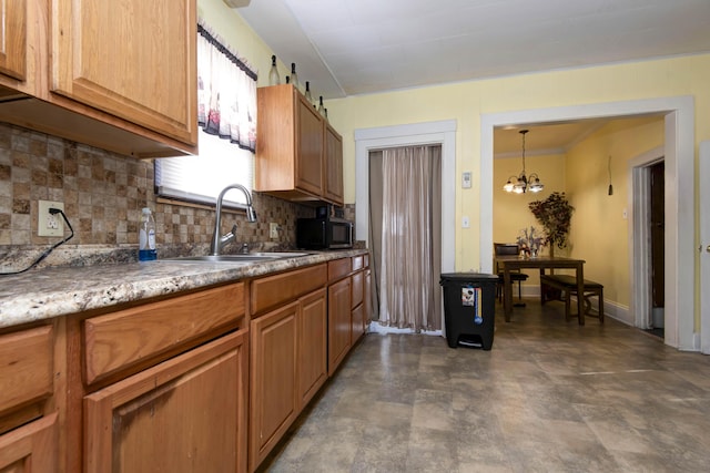 kitchen featuring backsplash, ornamental molding, sink, pendant lighting, and an inviting chandelier